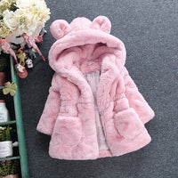 Pink children's coat with bear ears on a gray surface