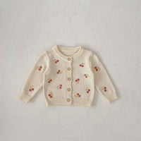 Beige cardigan with cherry patterns on a light gray background